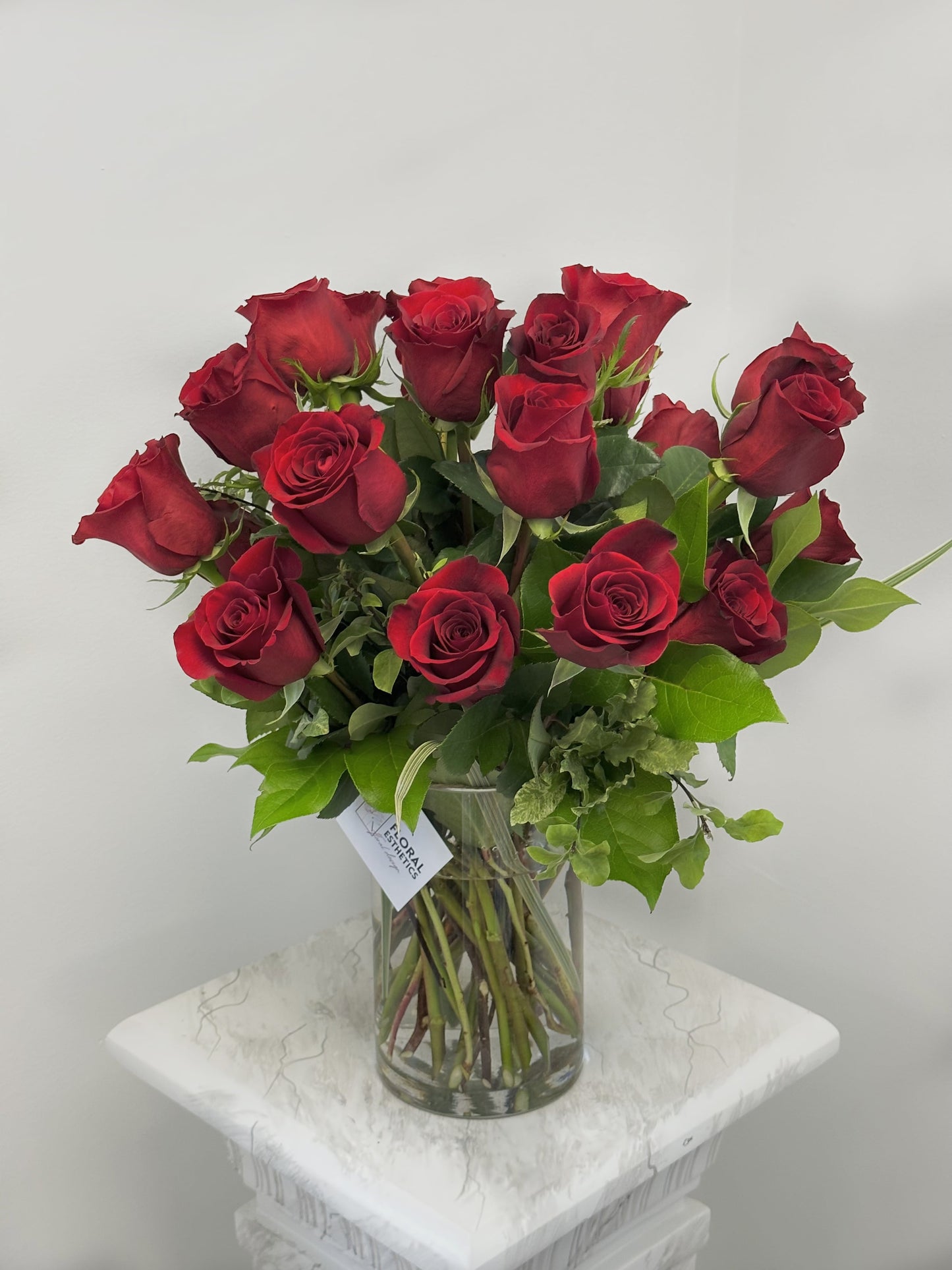 2 dozen red roses with greenery in clear cylinder by Floral Esthetics