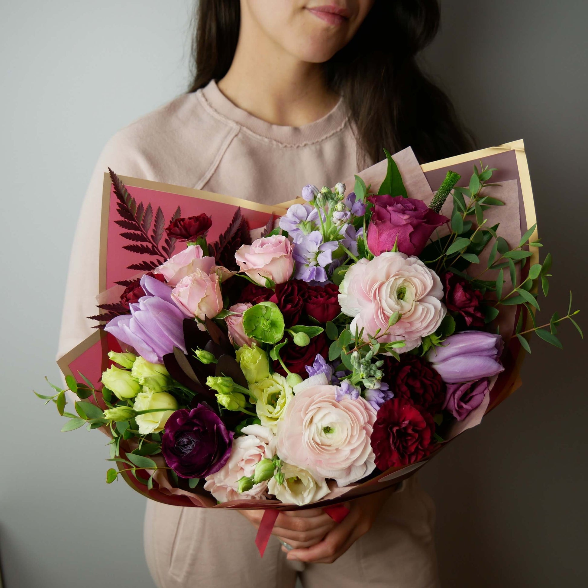 Burgundy and pink standard size wrapped bouquet featuring ranunculus, roses, tulips and other by Floral Esthetics