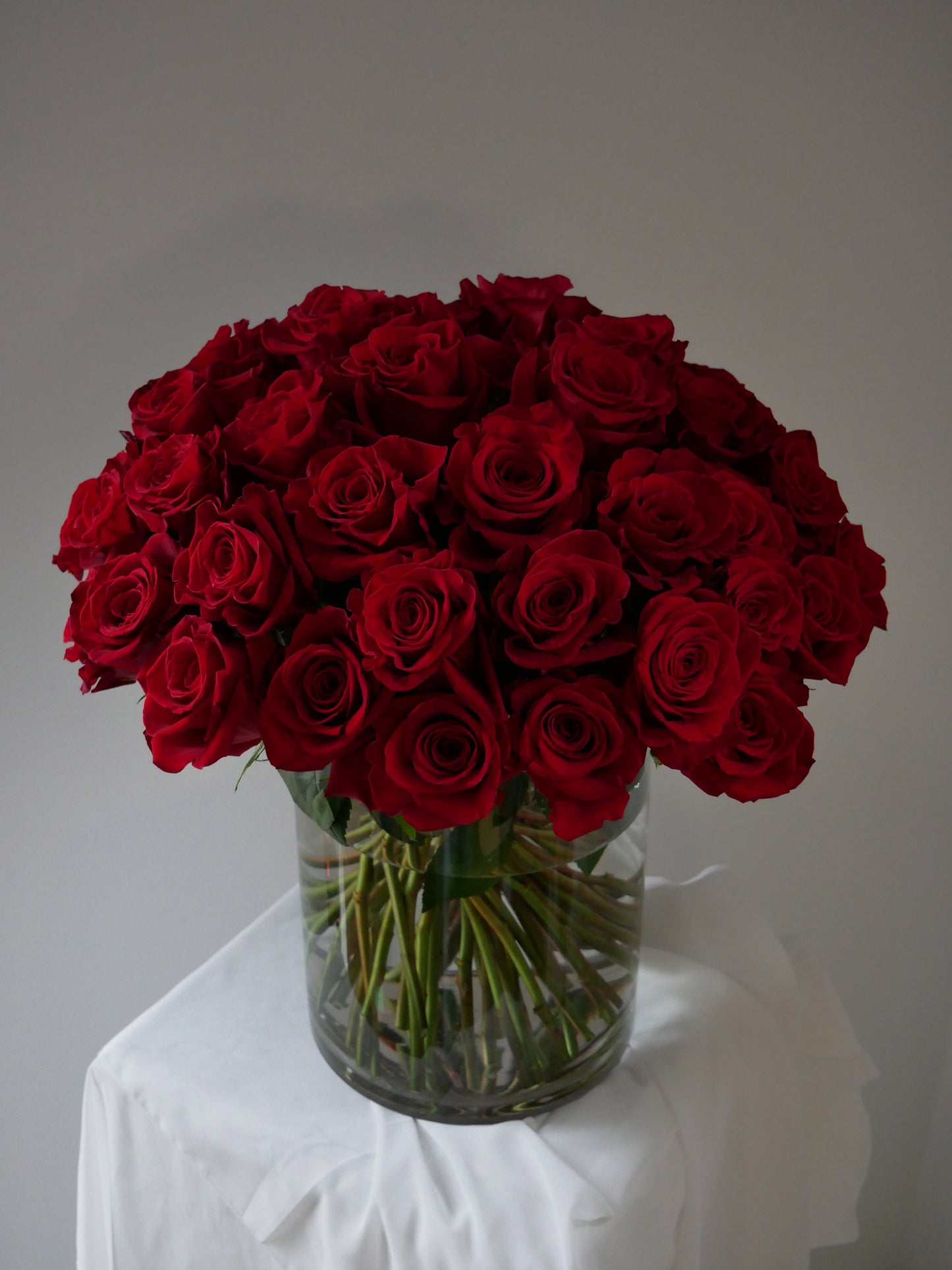 4 Dozen red roses in clear cylinder by Floral Esthetics