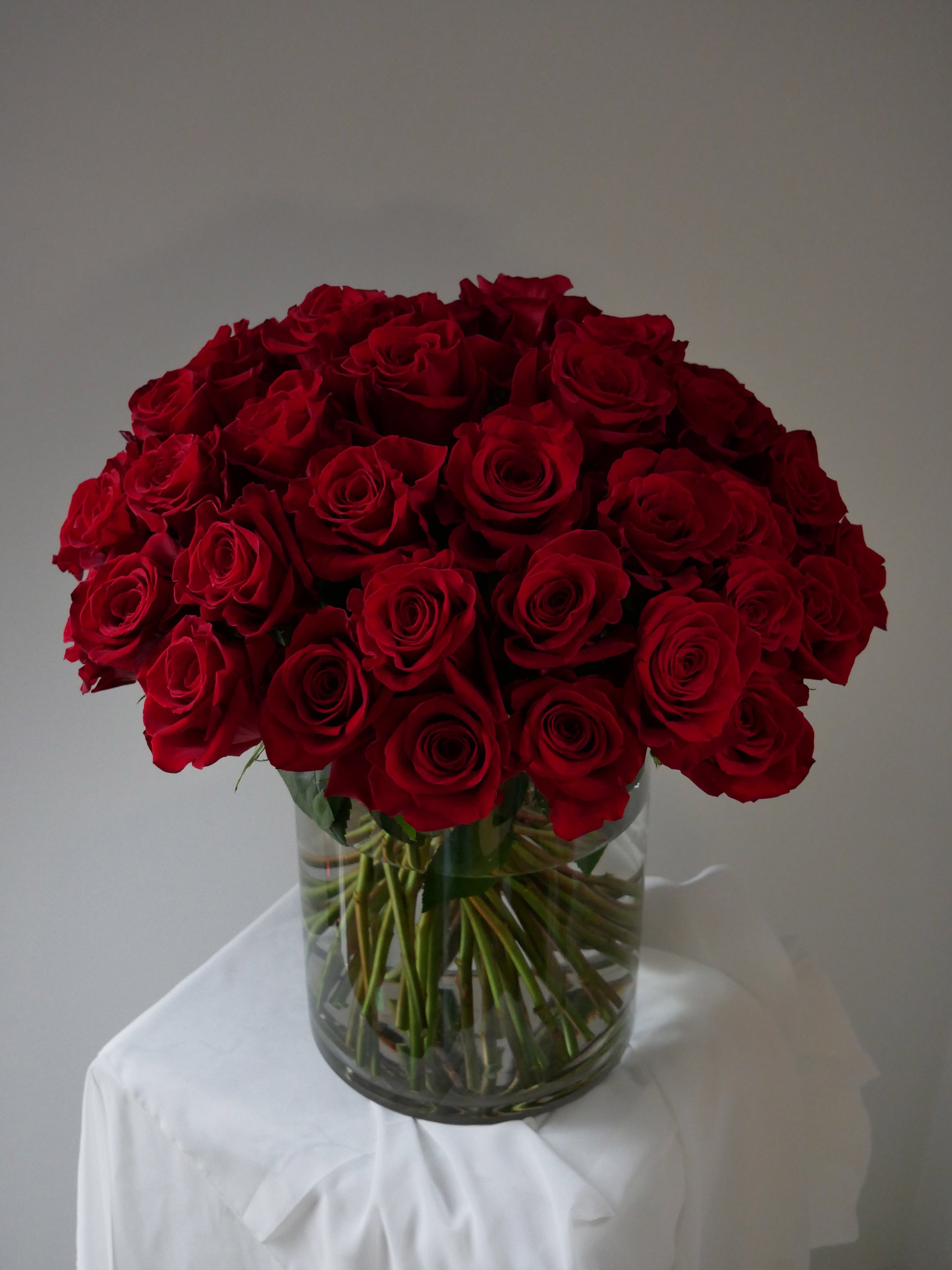 4 Dozen red roses in clear cylinder by Floral Esthetics