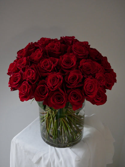 4 Dozen red roses in clear cylinder by Floral Esthetics