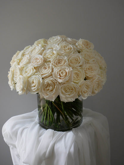 4 Dozens white roses in clear cylinder by Floral Esthetics