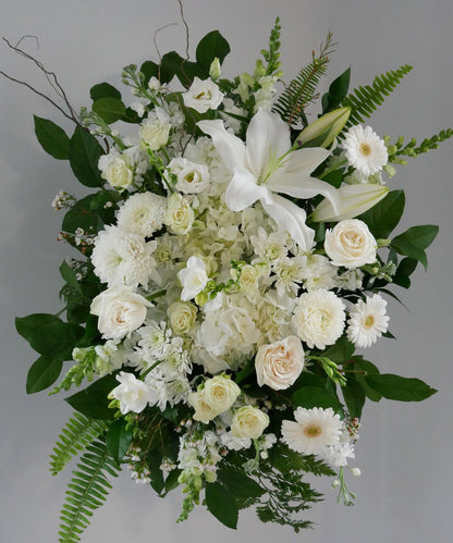 Funeral white spray featuring hydrangea, lilies, roses, chrysanthemum, gerberas and greens
