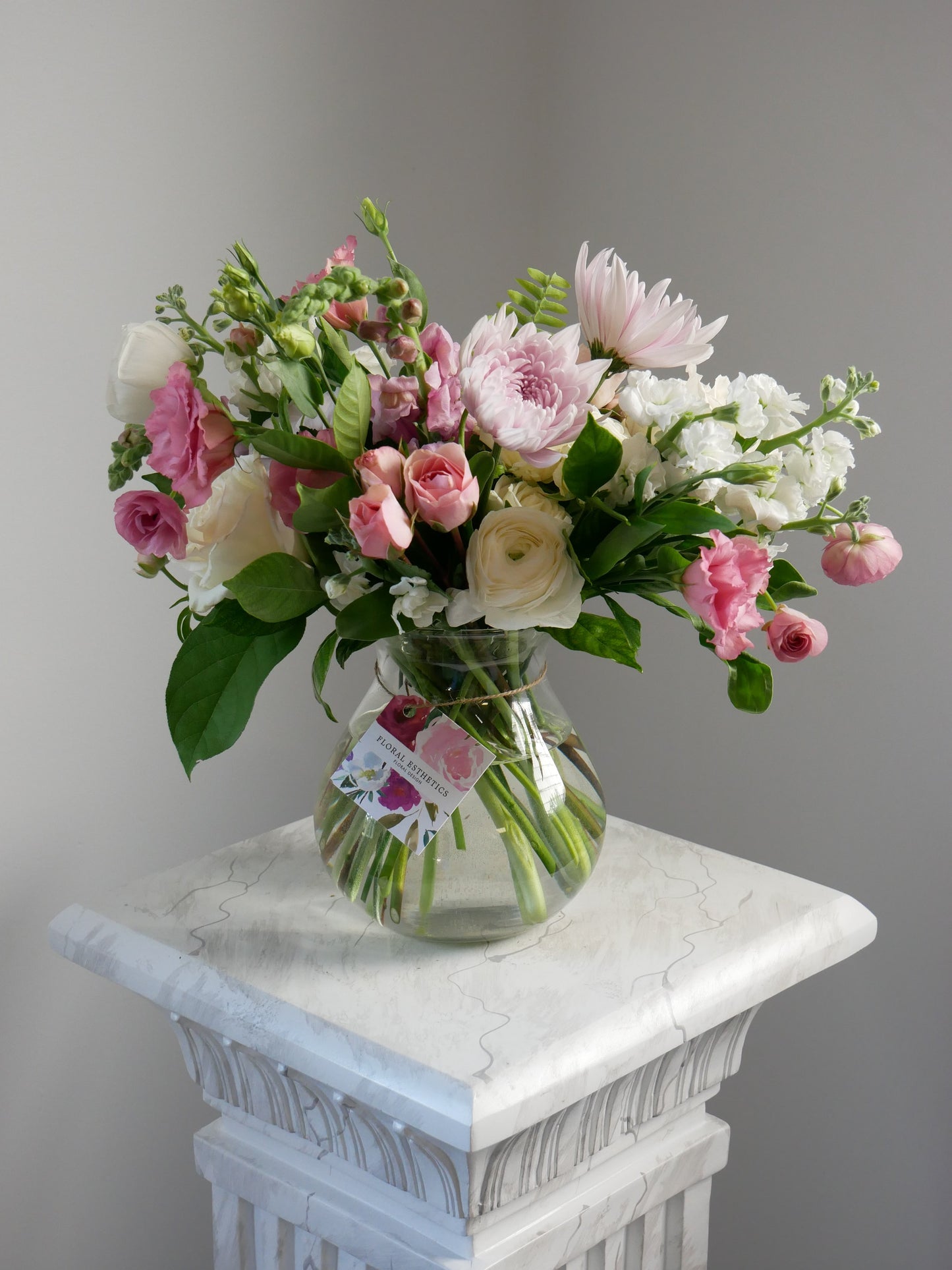 Pink and white standard size flower arrangement in clear vase featuring ranunculus, chrysanthemum, roses and more