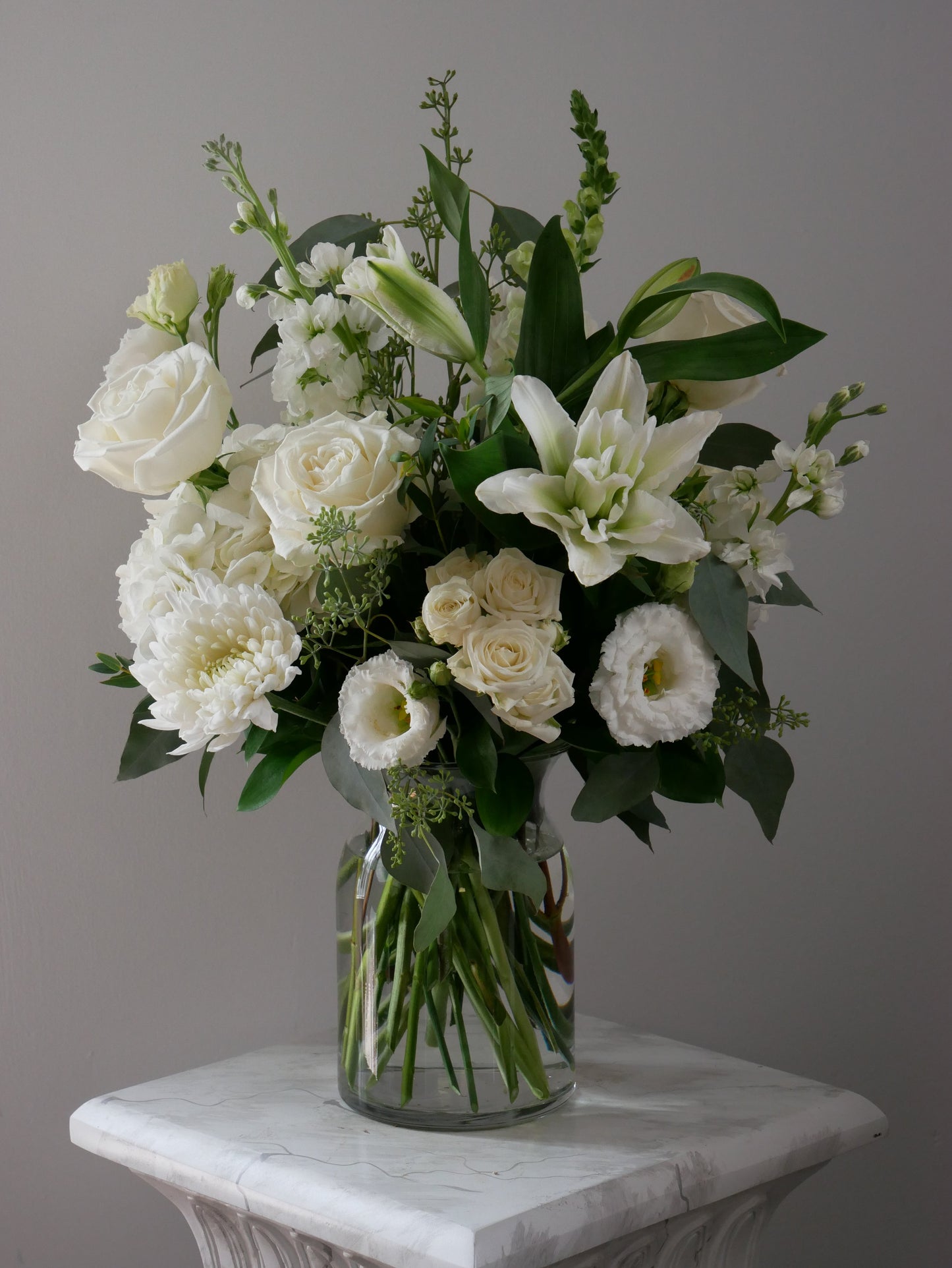 Sympathy arrangement in clear vase featuring lilies, roses, chrysanthemum, lisianthus, and more by Floral Esthetics