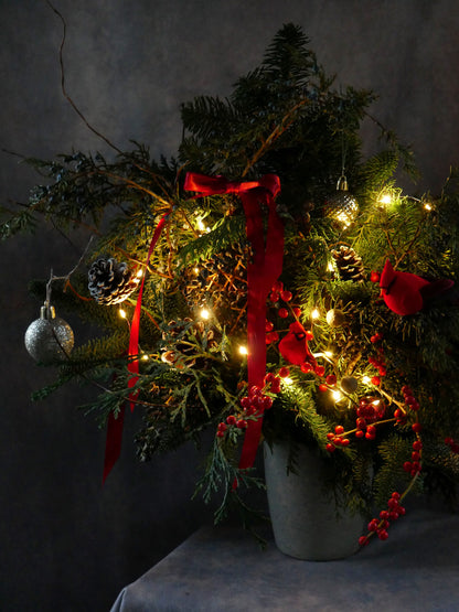 Close up on Christmas Magic arrangement featuring noble fir, Incense cedar, pine tree, Ilex berries, pine cones and matching color toys. By Floral Esthetics