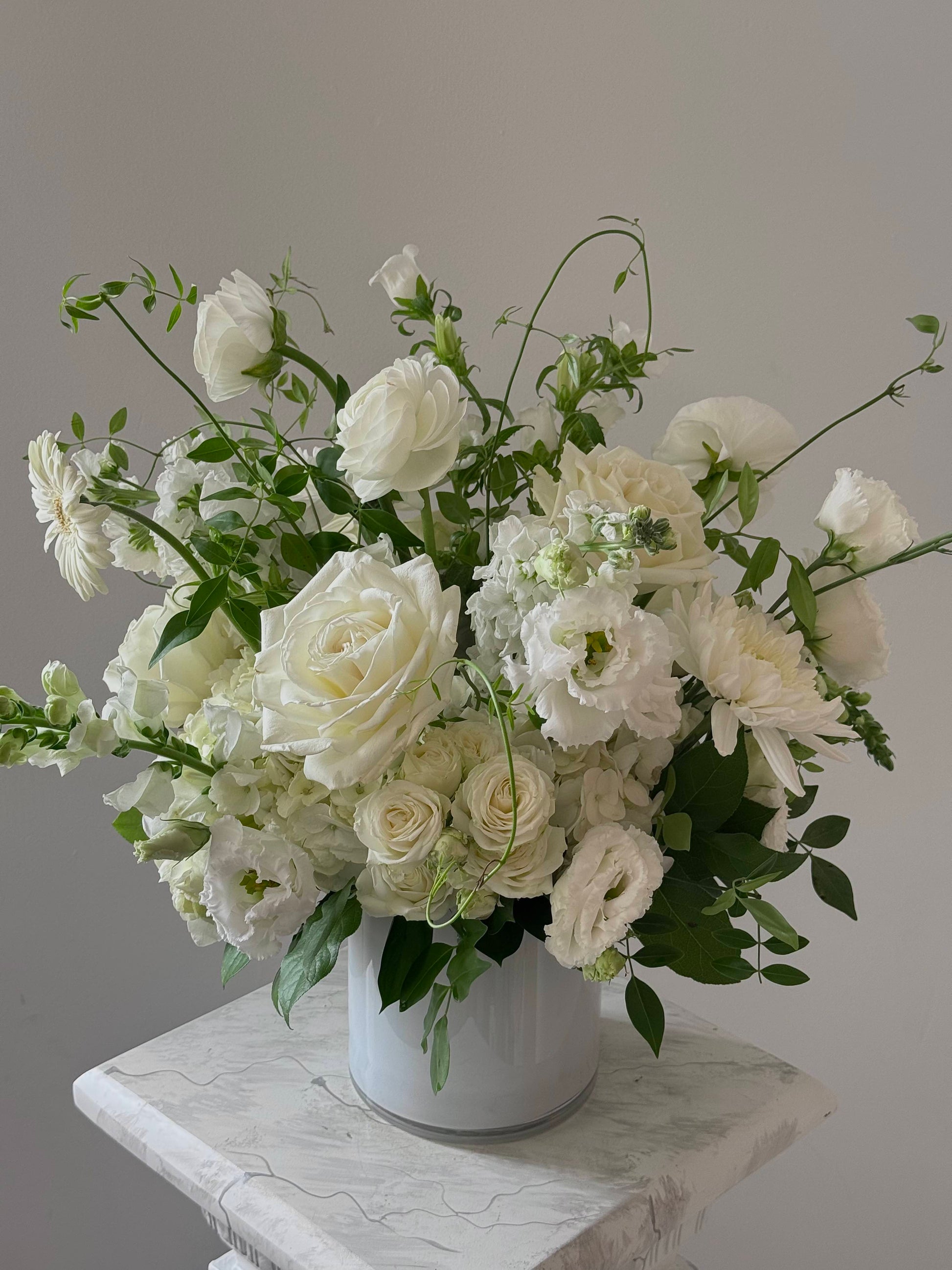 Bouquet of white flowers in a vase on a marble surface with a gray background