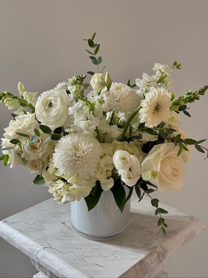 Bouquet of white flowers in a white vase on a marble surface with a neutral background