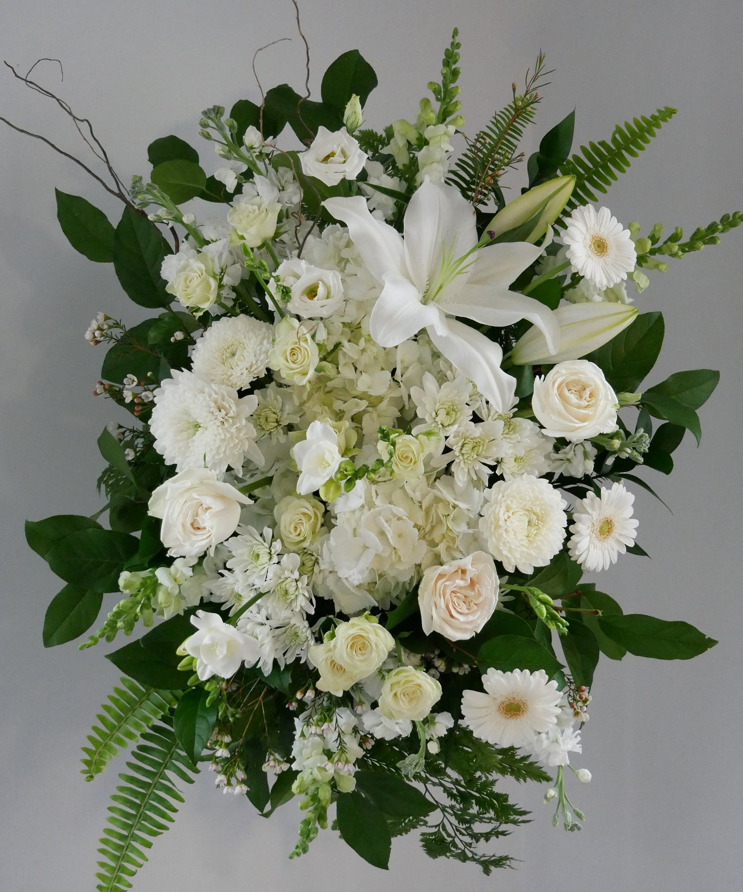 Funeral white spray featuring hydrangea, lilies, roses, chrysanthemum, gerberas and greens by Floral Esthetics