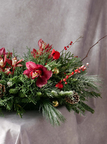 Close-up #2 on Holiday Centerpiece with Orchids and Seasonal greens and berries and also featuring Christmas ornaments and toys. By Floral Esthetics