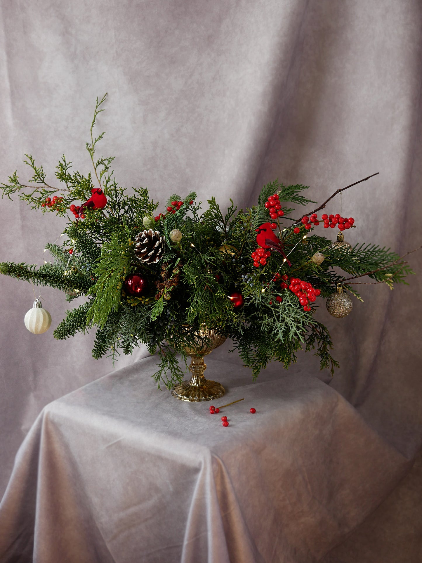 Christmas Centerpiece in Golden Compote with Lights, Christmas greens, berries and ornaments by Floral Esthetics