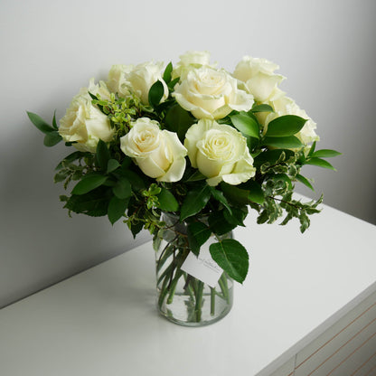 1 dozen white roses with greenery in clear vase by Floral Esthetics