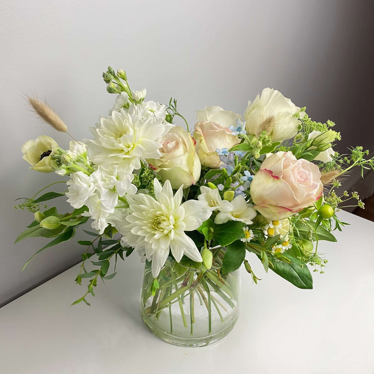 Premium size cape style flower arrangement in clear vase featuring dahlias, roses, twedia, wild greens and other stuff