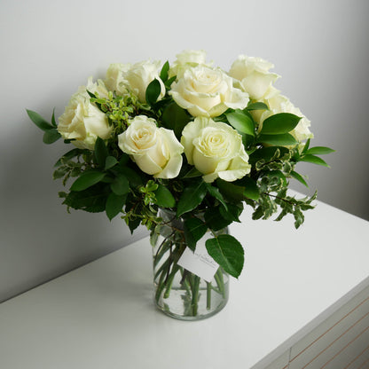 1 dozen white roses with greenery in clear vase