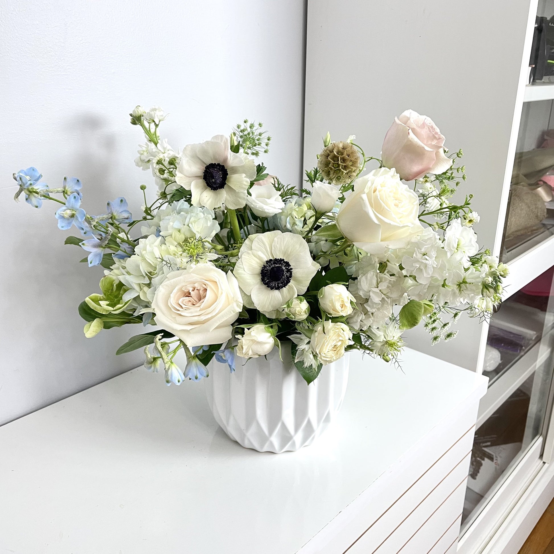 Luxury cape style flower arrangement in white vase featuring anemone, delphinium, hydrangea, lizianthus, roses and other 
