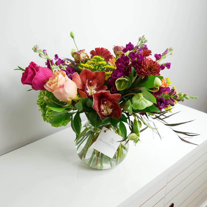 Premium red, pink and orange flower arrangement in clear vase