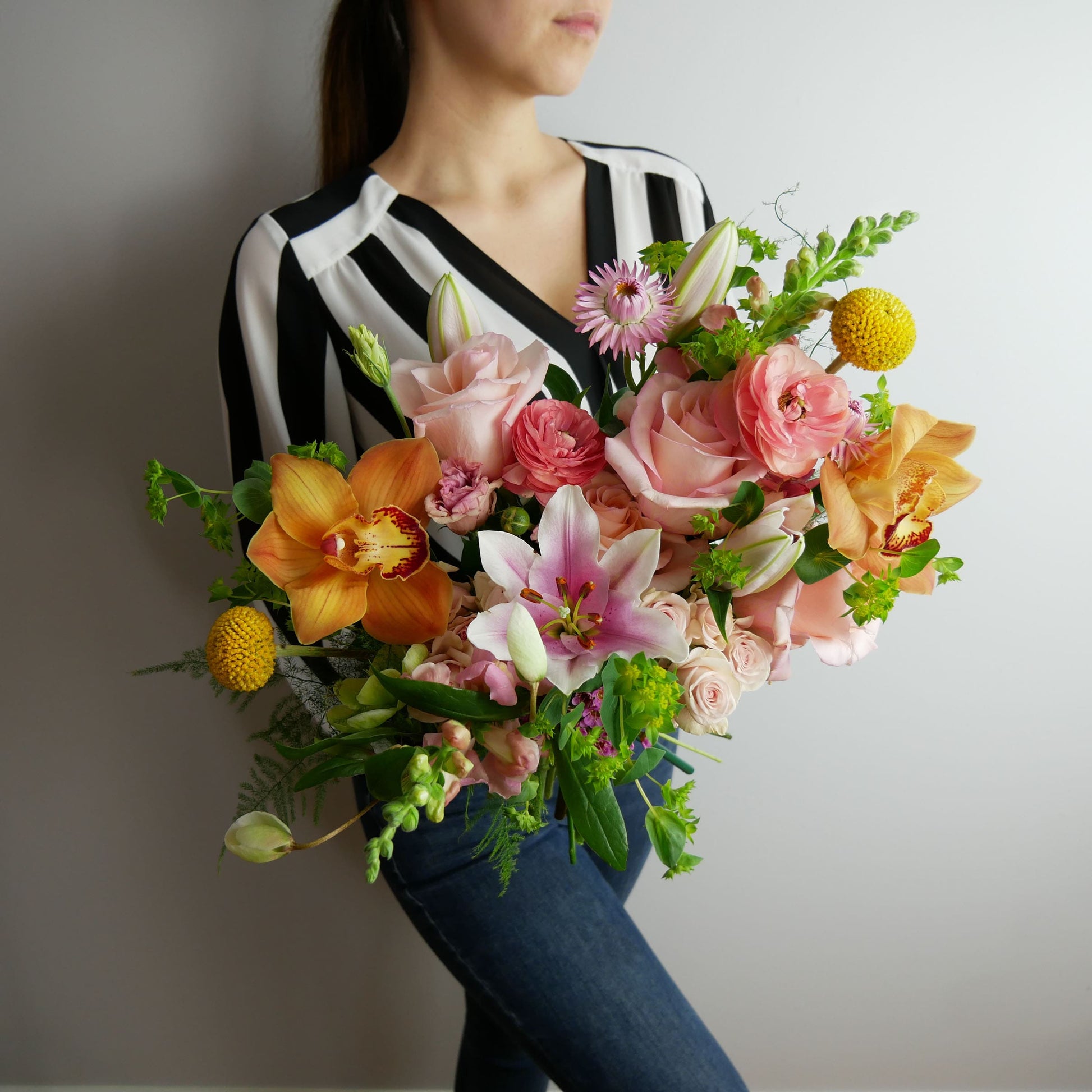 Bright tropical bouquet featuring orchids, lilies, ranunculus, craspedia, roses, snap dragon and much more