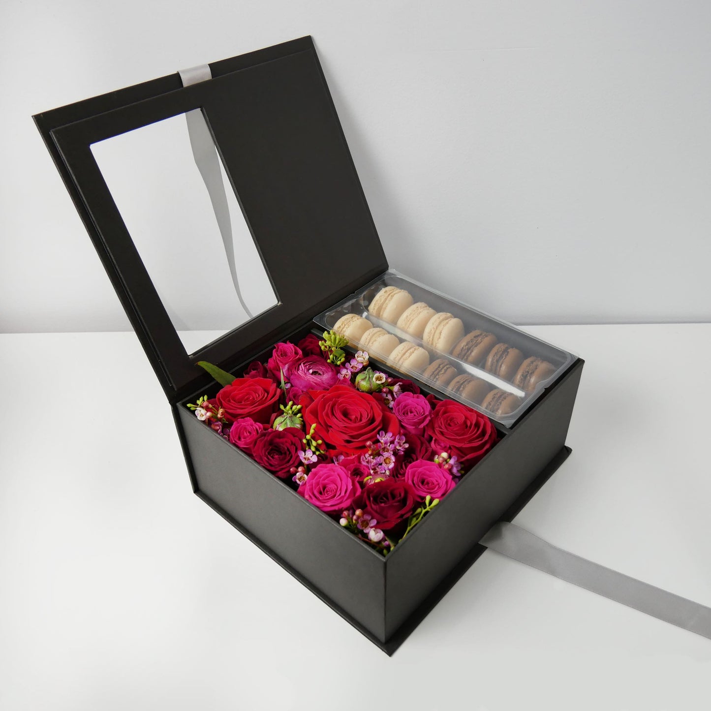 black flower box with macarons featuring red and hot pink roses