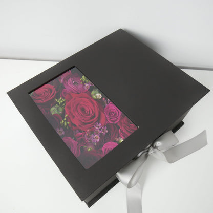Black flower box with closed cover featuring red and hot pink roses