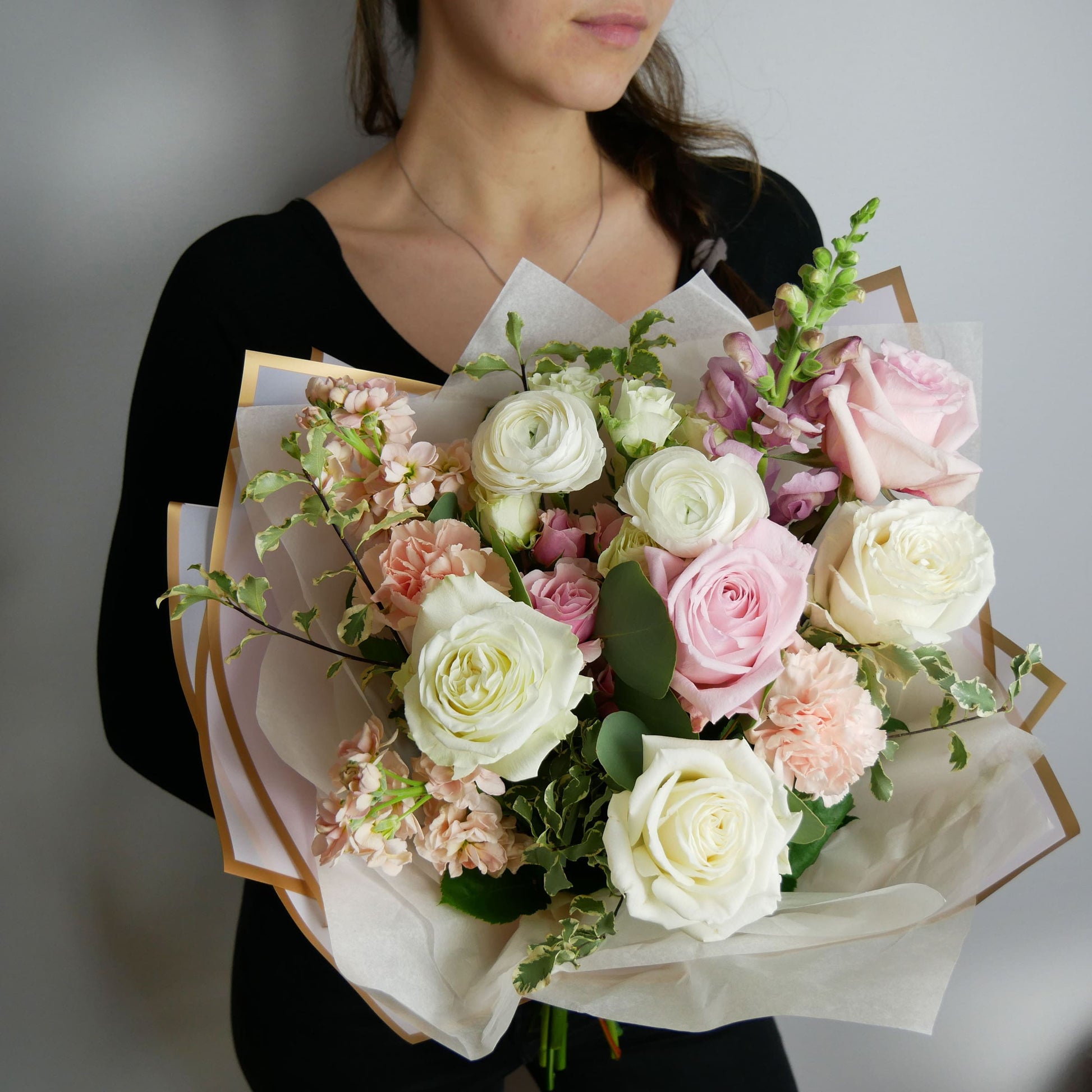 Tender pink and white wrapped bouquet featuring ranunculus, roses, stock and more