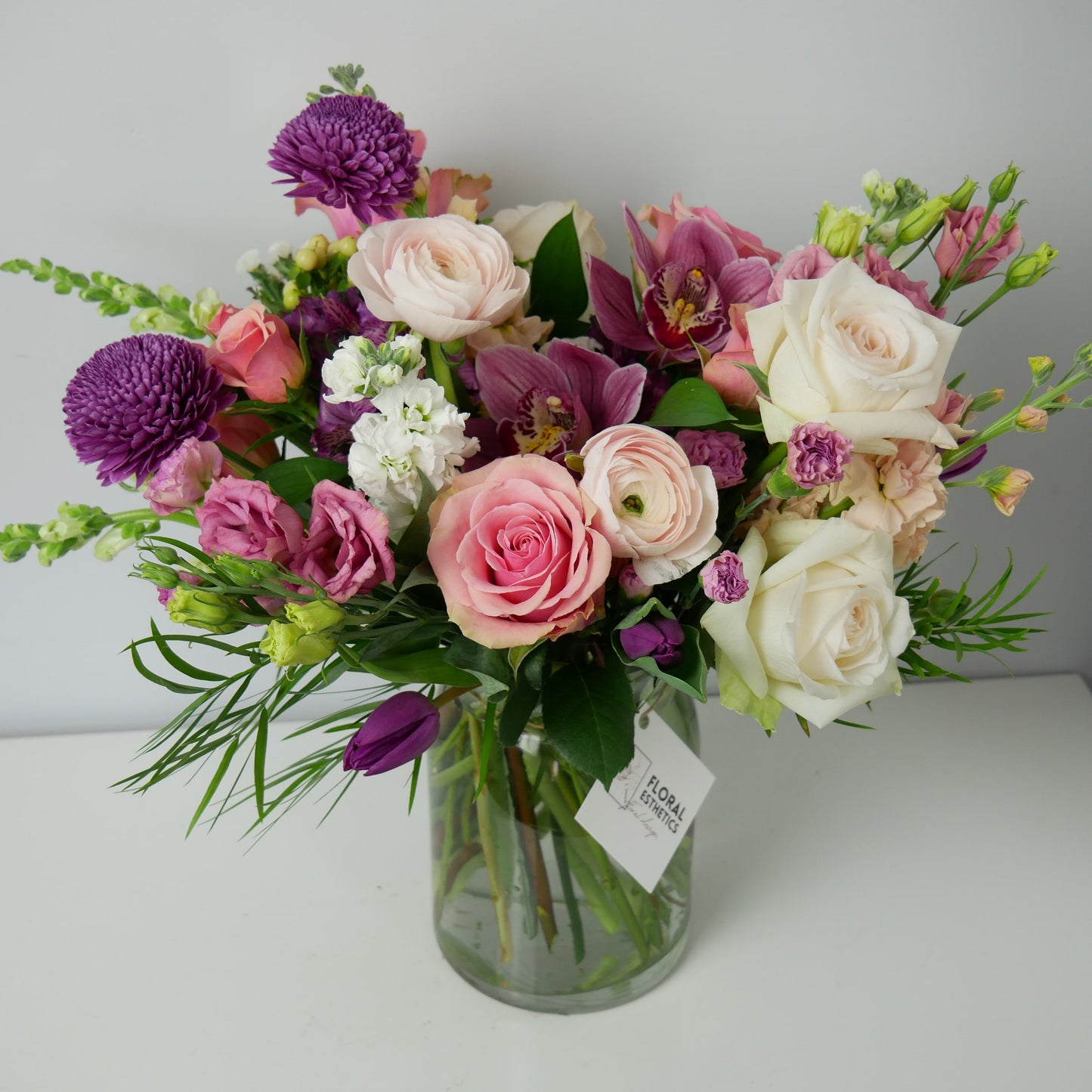 Purple, white and pink premium size flower arrangement featuring orchids, ranunculus, roses, chrysanthemum and much more