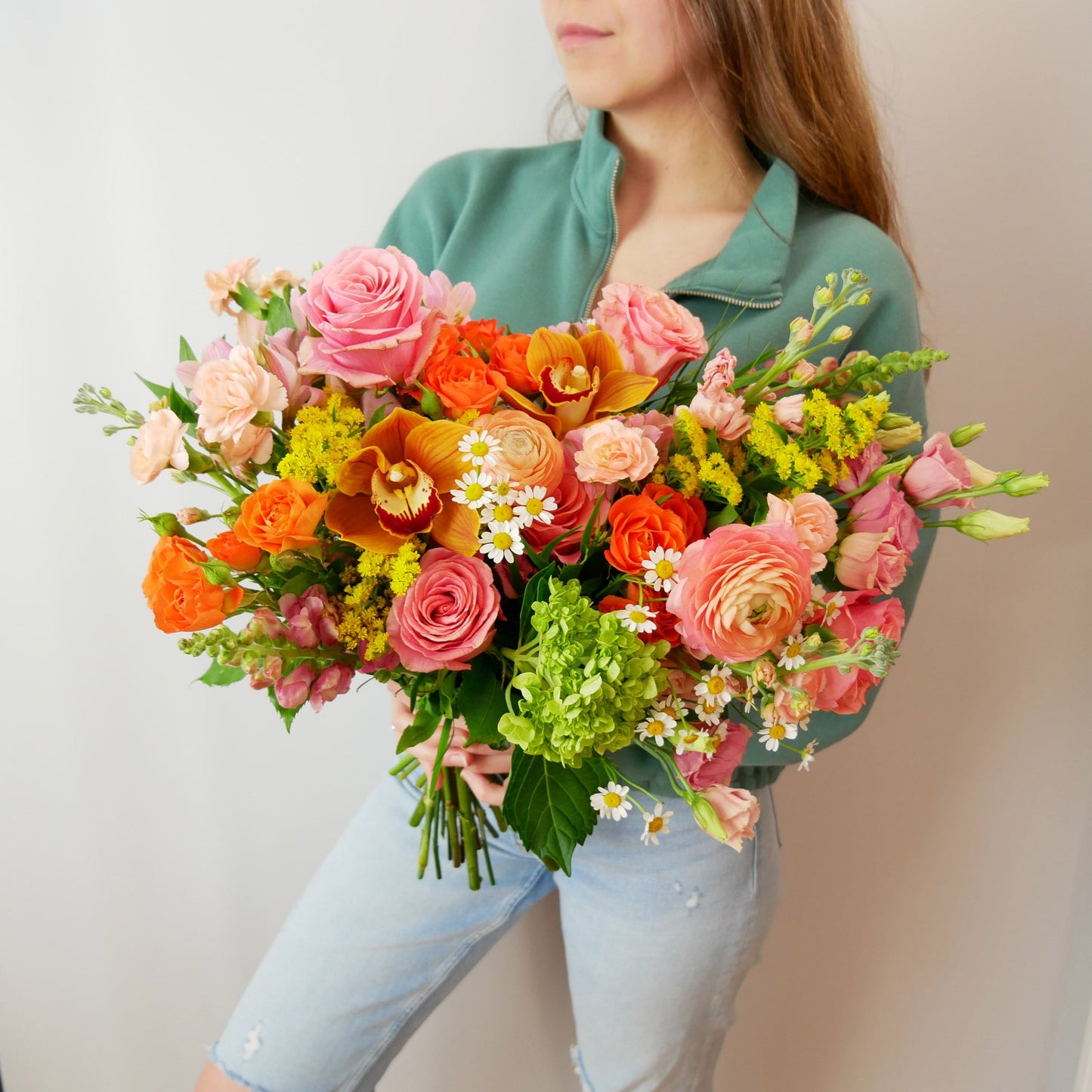 Premium size bouquet featuring orange orchids, peach ranunculus, pink roses and more