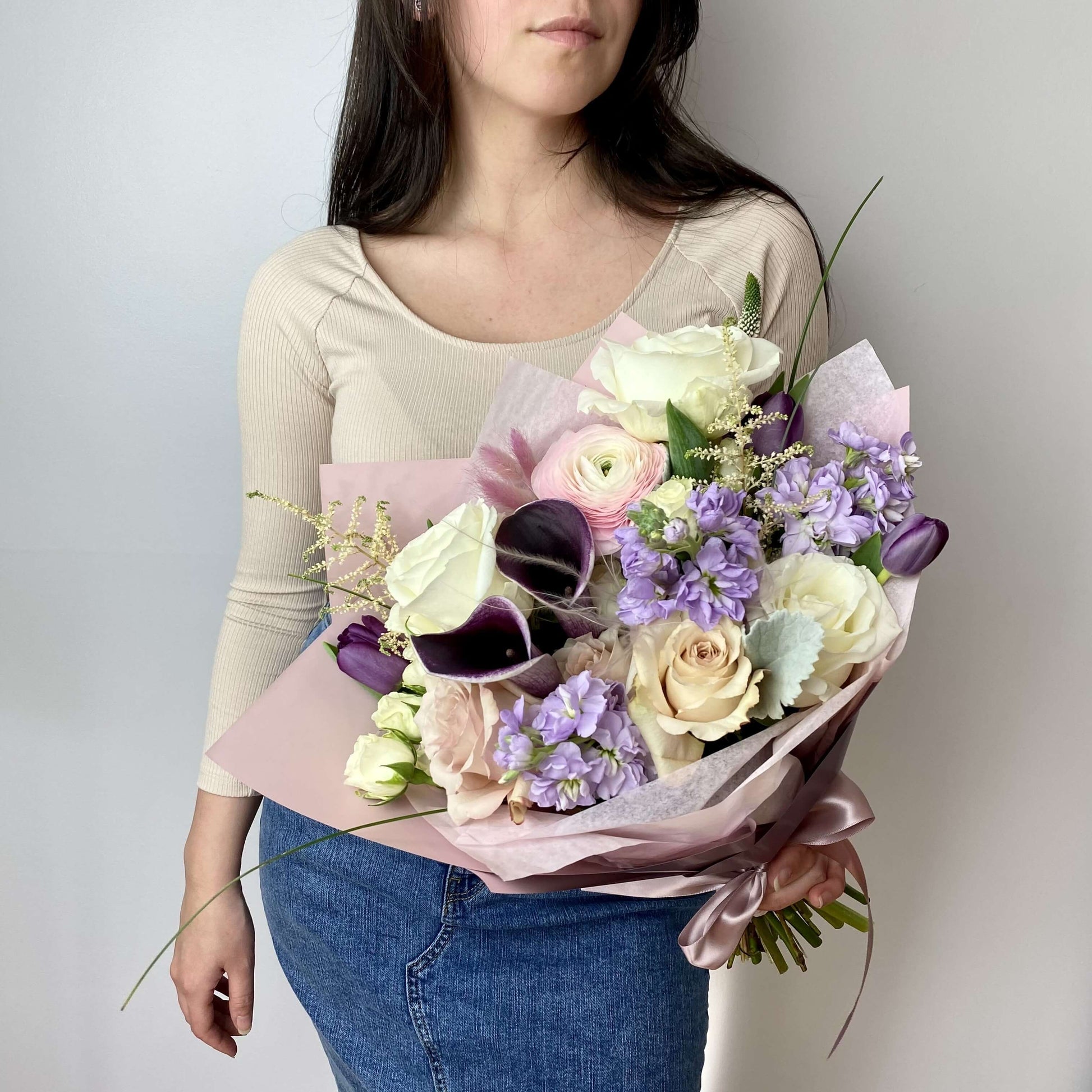 white and purple standard size bouquet wrapped in purple pink paper and featuring calla lilies, ranunculus and roses 