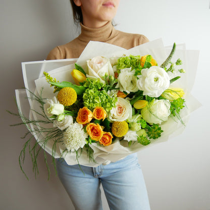 Premium size wrapped bouquet in white, green and yellow colors. Featuring ranunculus, roses, hydrangeas, greens and more by Floral Esthetics - Barnstable florist