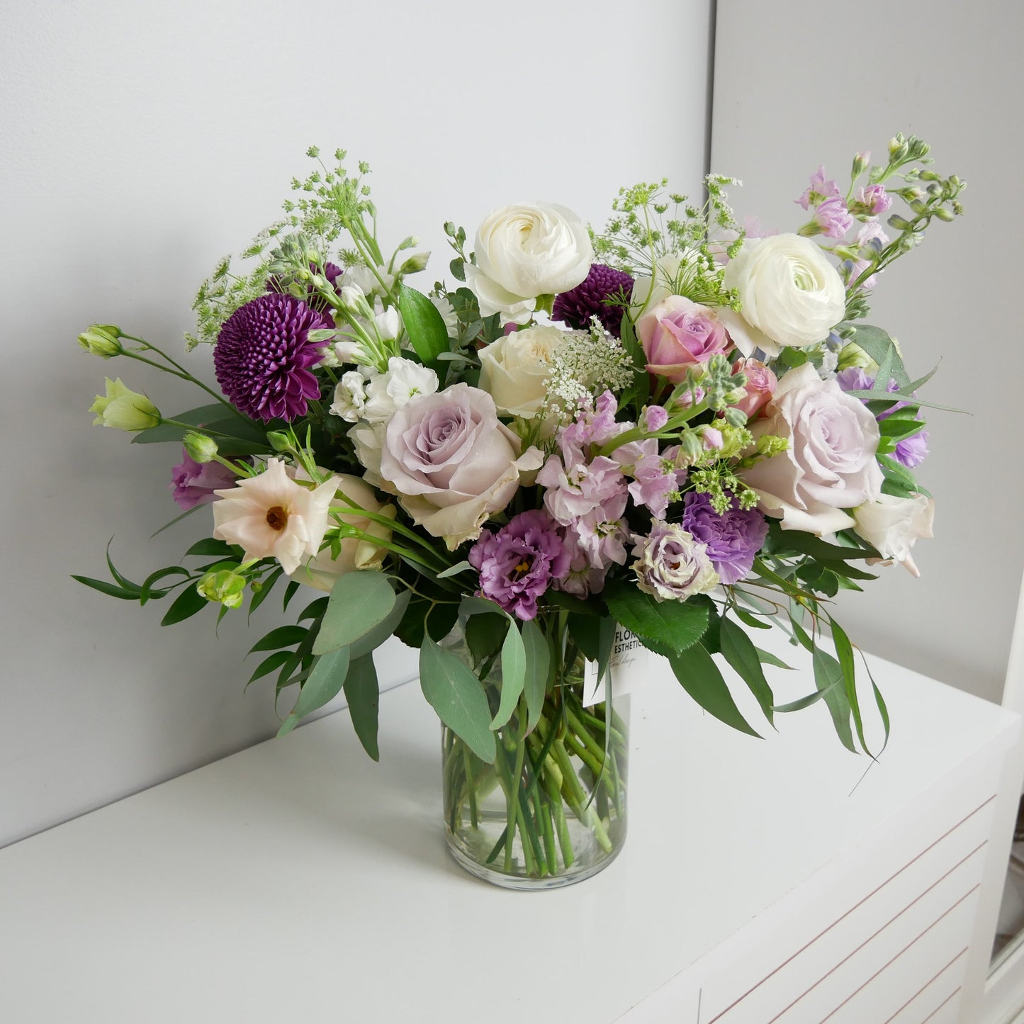 Luxury white and purple flower arrangement featuring ranunculus, roses, lisianthhus and eucalyptus by Floral Esthetics