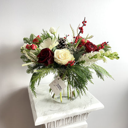 Merry Christmas Arrangement #3 featuring seasonal greens and blooms such as noble fir, Incense cedar, pine tree, Ilex berries, pine cones, roses, ranunculus, chrysanthemums and more. By Floral Esthetics   