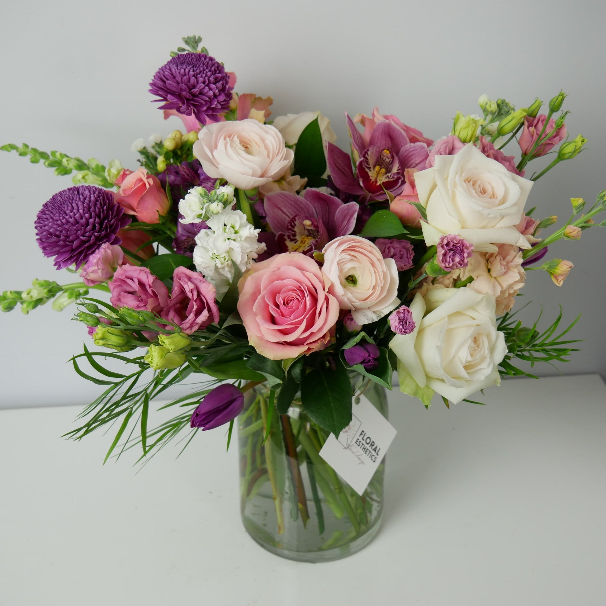 Purple, white and pink premium size flower arrangement featuring orchids, ranunculus, roses, chrysanthemum and much more by Floral Esthetics