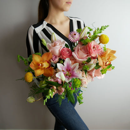 Bright tropical bouquet featuring orchids, lilies, ranunculus, craspedia, roses, snap dragon and much more by Floral Esthetics