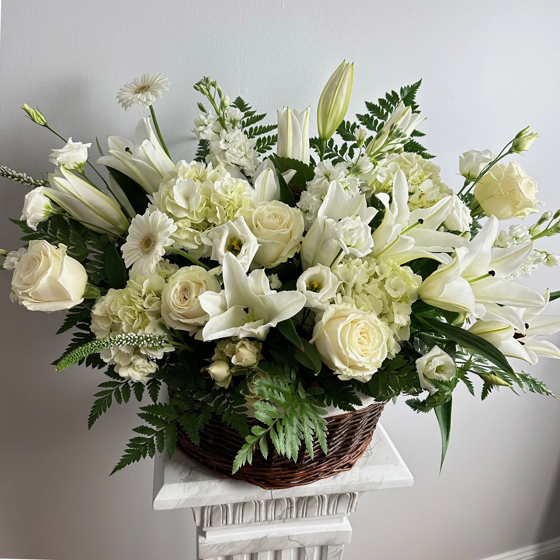 Large white sympathy floral basket featuring lilies, roses, hydrangeas, gerberas, greens and more by Floral Esthetics